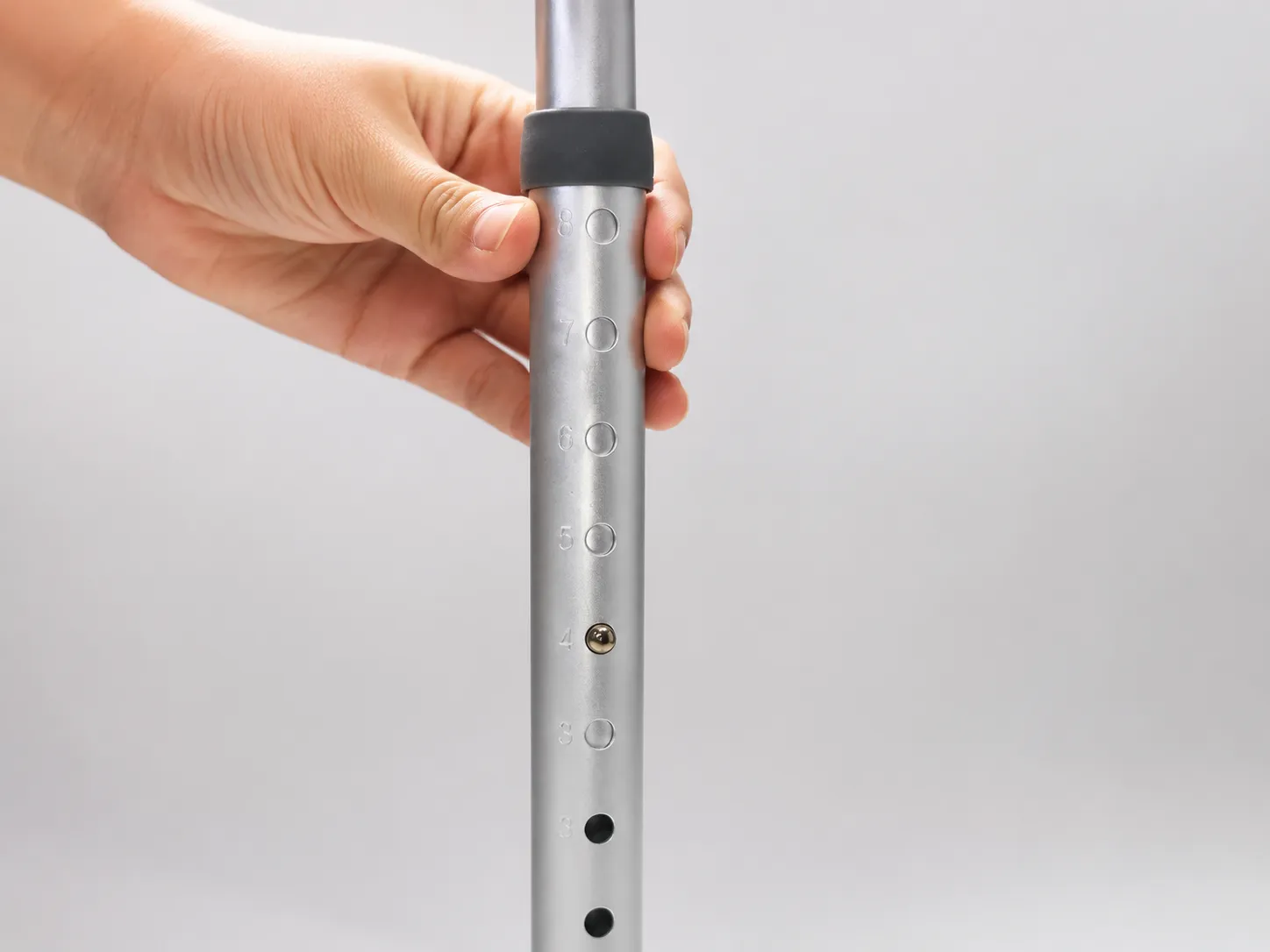 Close-up of the walking frame's numbered height-adjustment holes and grey adjustment collar on the lower leg.